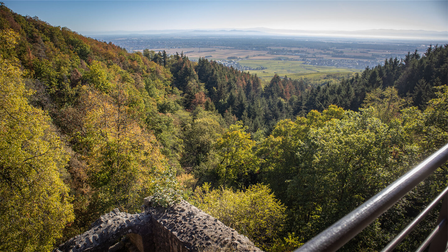 Blick über Mauerbogen und Geländer auf die bewaldeten Vogesen-Vorberge bei Wettolsheim