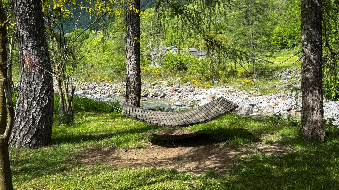 Zwischen den Bäumen gespannt, lädt die hölzerne Hängematte an der Verzasca zum Verweilen ein.