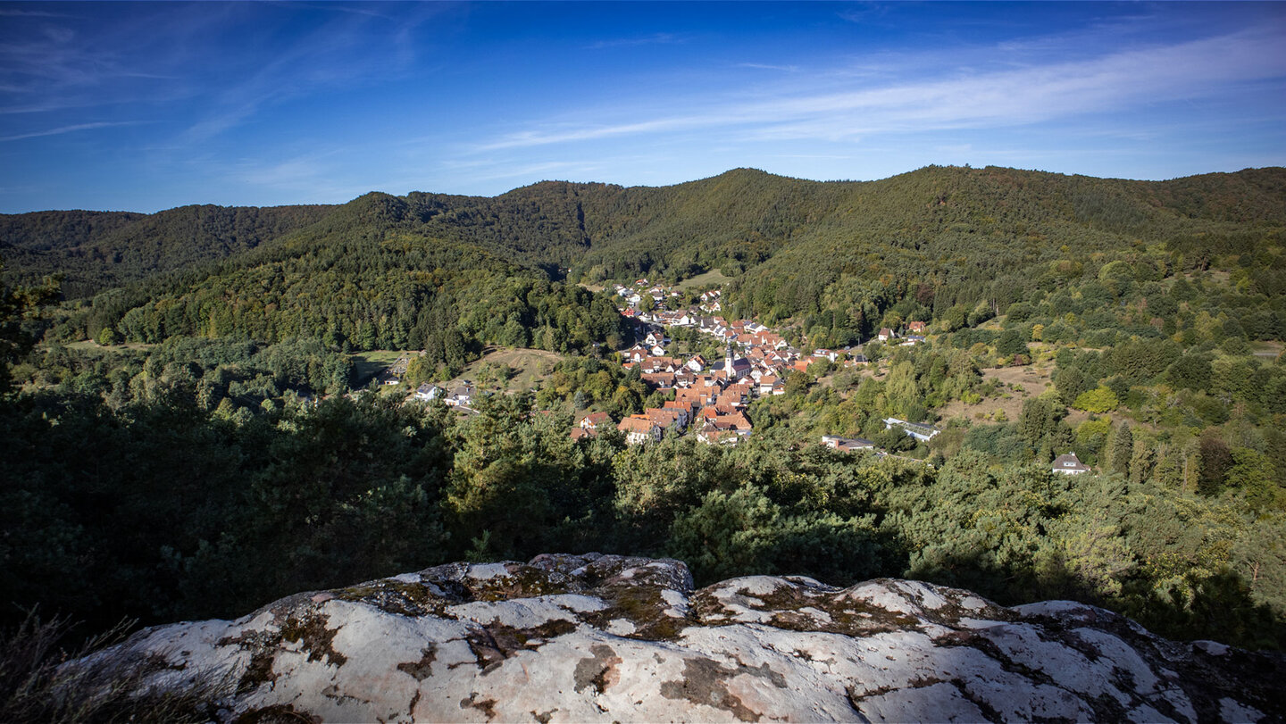 anoramablick vom Felsplateau des Hockersteins auf Schwanheim mit Kirche und roten Dächern im Tal, umgeben von bewaldeten Bergrücken des Wasgaus