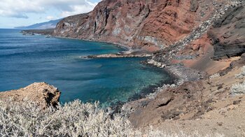 Blick entlang der rotgefärbten Vulkanküste an der Bahía de Naos
