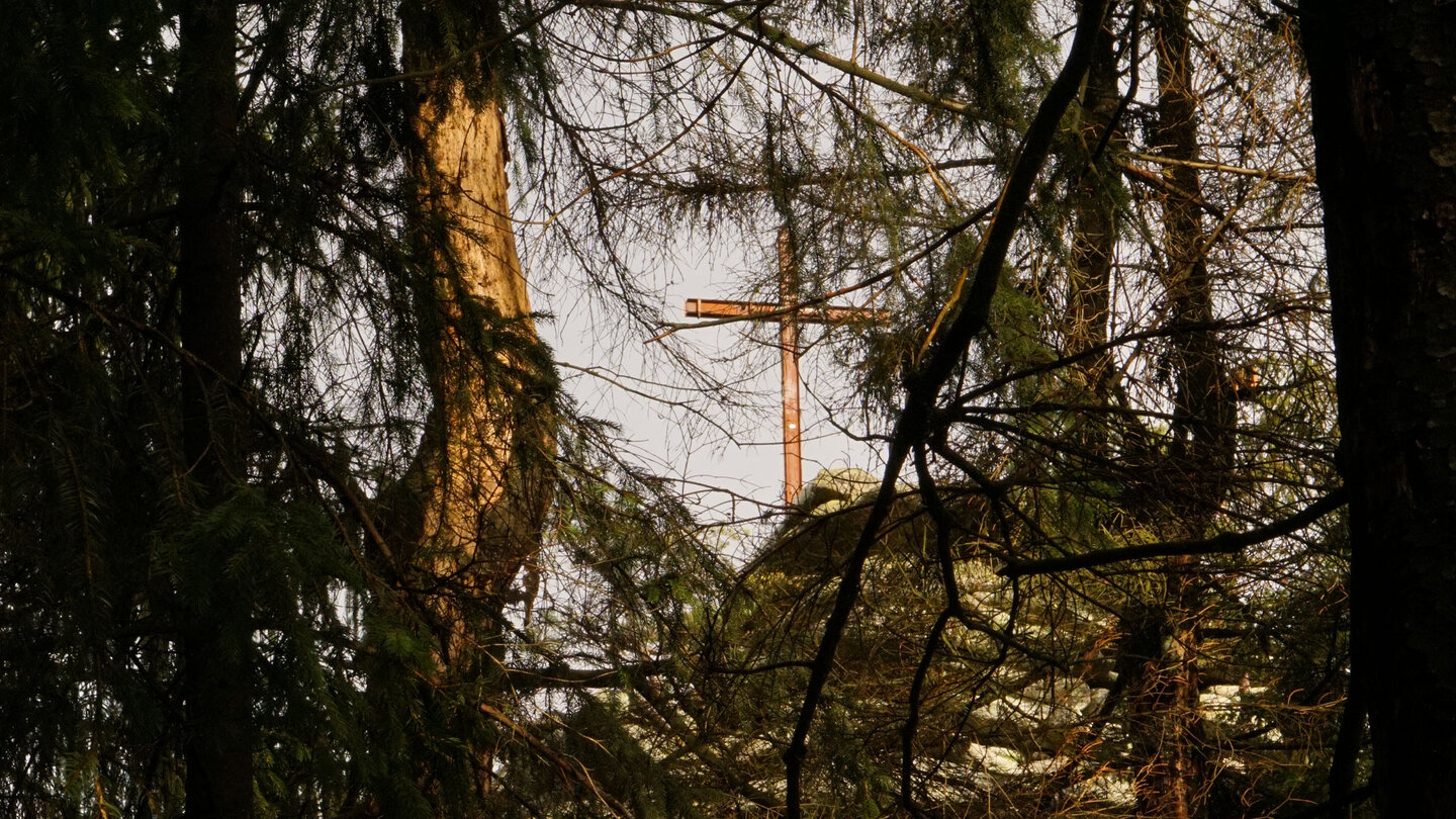 Blick durch den Wald zum Kreuz auf dem Rudolfstein Blick durch den Wald zum Kreuz auf dem Rudolfstein