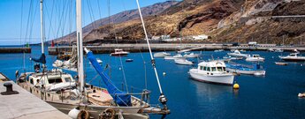 Segelboot vor der Kulisse der zum Meer hin abfallenden Berghänge am Puerto de la Estaca auf El Hierro