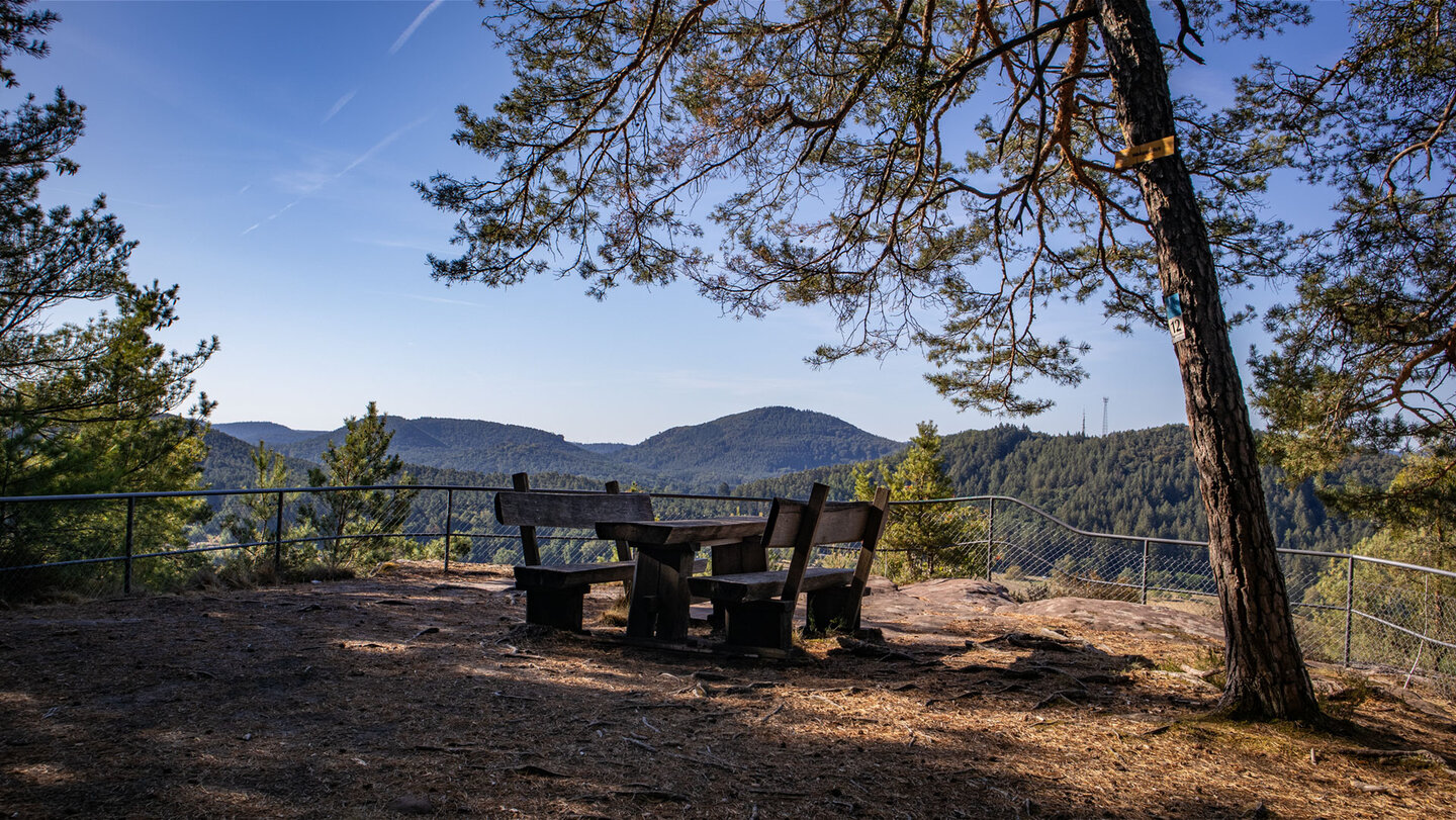 Holzsitzgruppe am gesicherten Aussichtspunkt Wasgaublick auf einer Buntsandsteinplattform, Panorama über bewaldete Berge