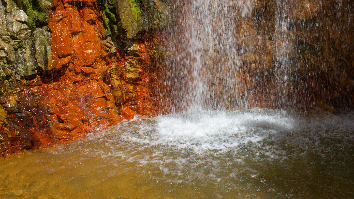 Farbenspiel zwischen Rot- und Grüntönen am Wasserfall