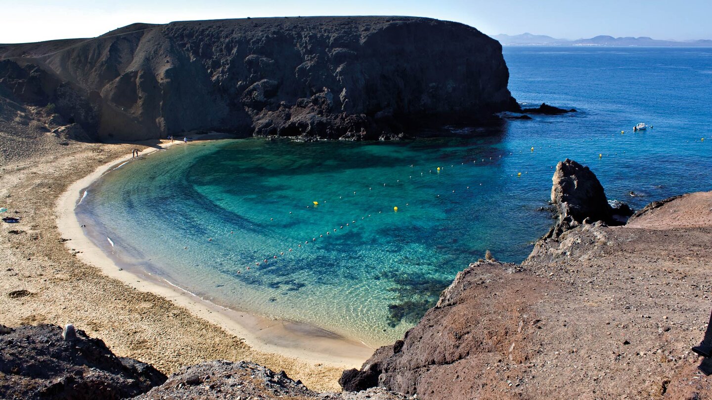 der Strand Playa de Papagayo auf Lanzarote mit türkiesgrünem Wasser und der Insel Fuerteventura im Hintergrund