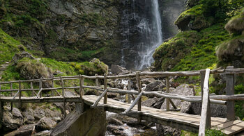 eine Holzbrücke führt über das Wasser bei der Cascata La Froda im Valle Verzasca