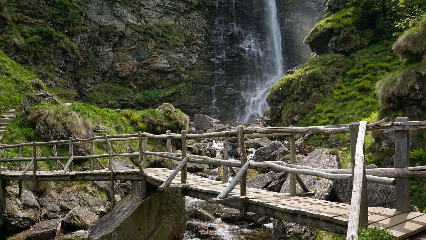 eine Holzbrücke führt über das Wasser bei der Cascata La Froda im Valle Verzasca