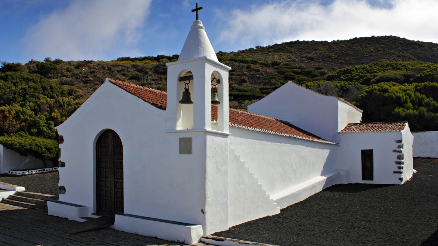 die strahlend weiße Ermita Virgen de los Reyes vor grün bewaldeten Hängen