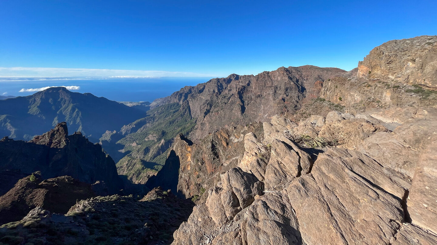 Blick über schroffe Felsformationen auf die Gipfelkette der Caldera