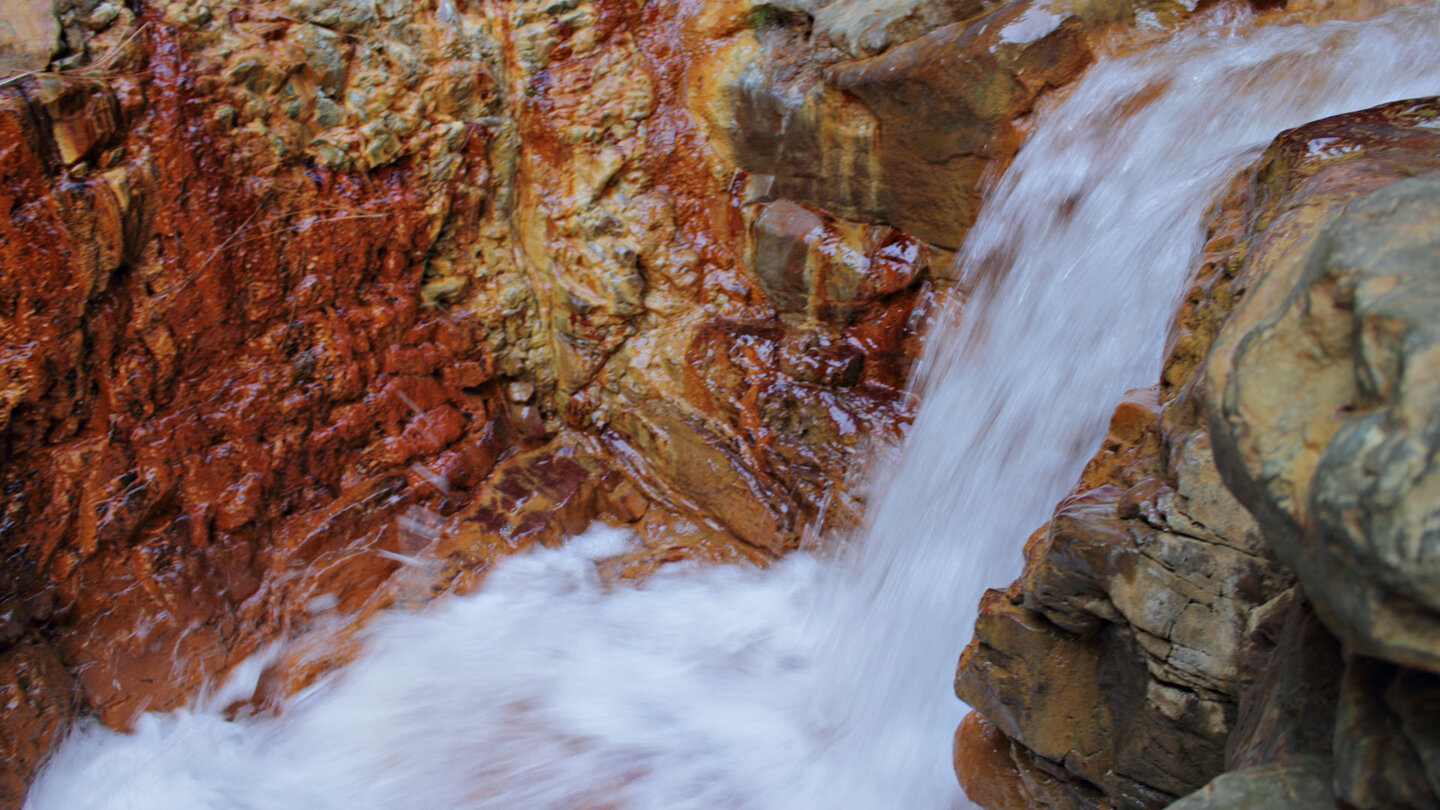 reißendes Wasser zwischen rotem Felsgestein an der Cascada de Colores