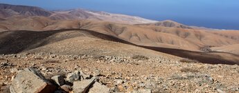 der Wanderweg GR 131 steigt durch eine sanfte Hügellandschaft von Pajára auf