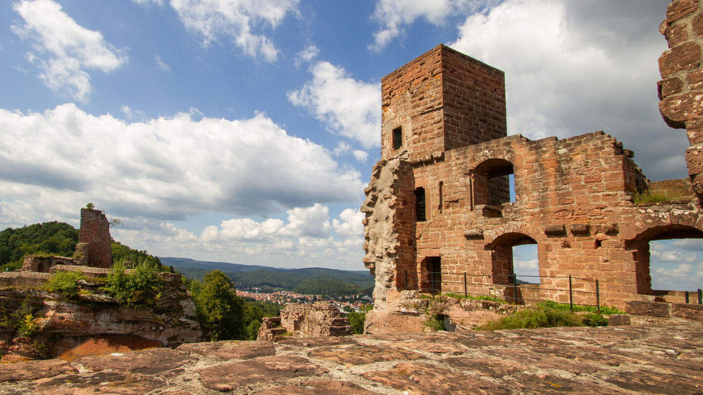 Mehrstöckige Mauerreste des Palasturms der Burg Altdahn mit Fenster- und Bogenöffnungen, im Hintergrund die Ruine Tanstein und der Blick auf Dahn