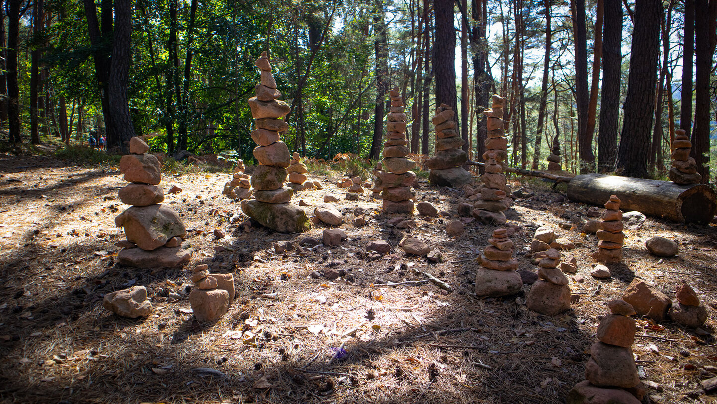Wegkreuzung am Weimersberg mit vielen kleinen und großen Steintürmen aus Sandstein, dahinter lichter Kiefernwald
