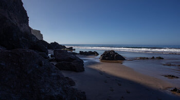 steil abfallende Klippen am feinen Sandstrand der Playa de Güigüí