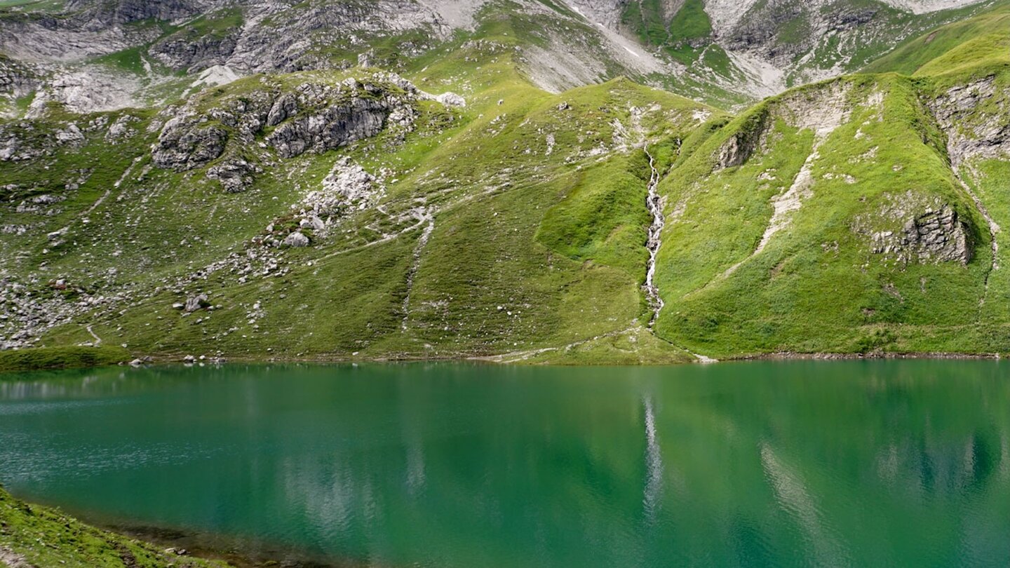 im smaragdgrünen See spiegeln sich die umliegenden Gipfel Spiegelungen der Gipfel im See