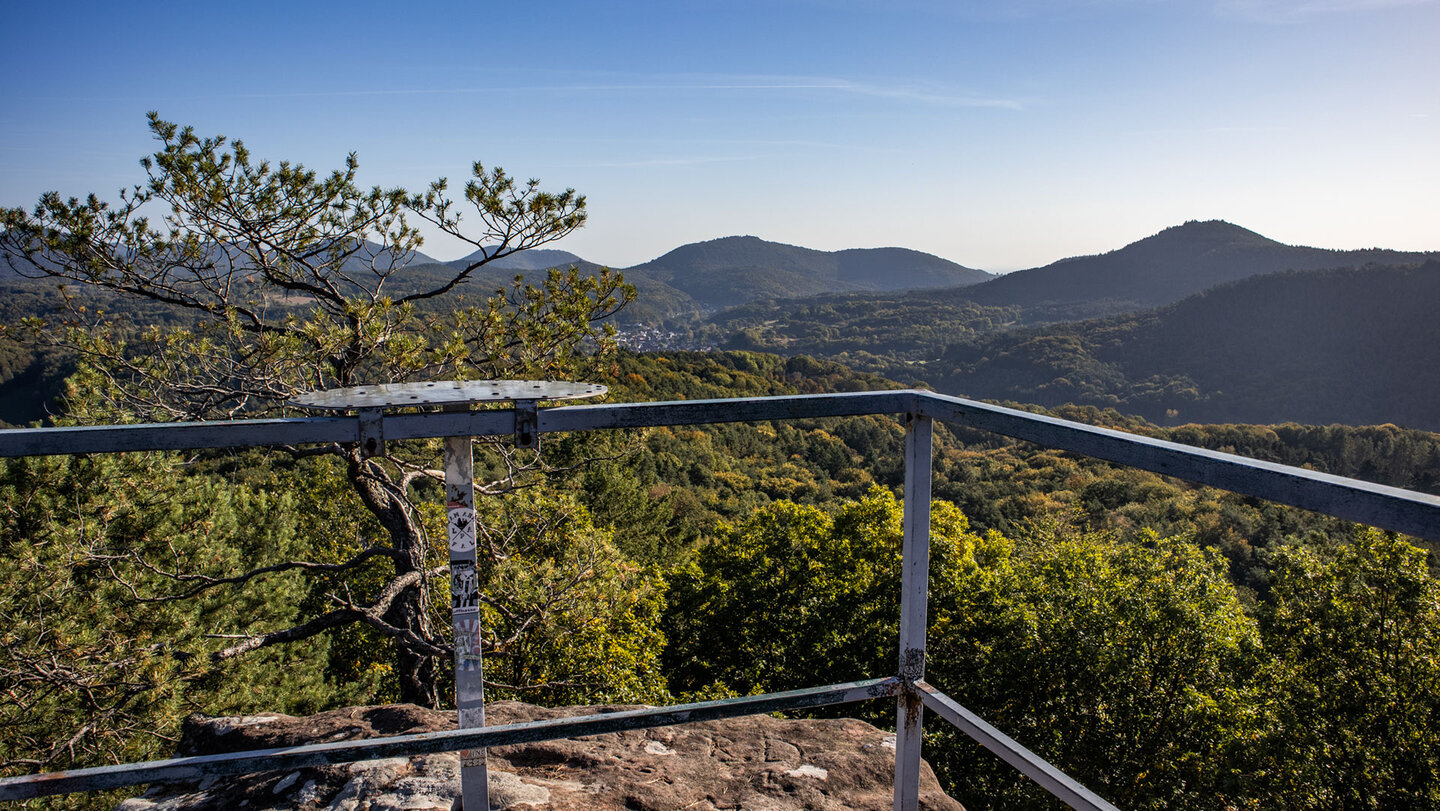 Blick von der gesicherten Plattform des Schweinsfels bei Silz über Waldkuppen und Dörfer des Trifelslands unter blauem Himmel