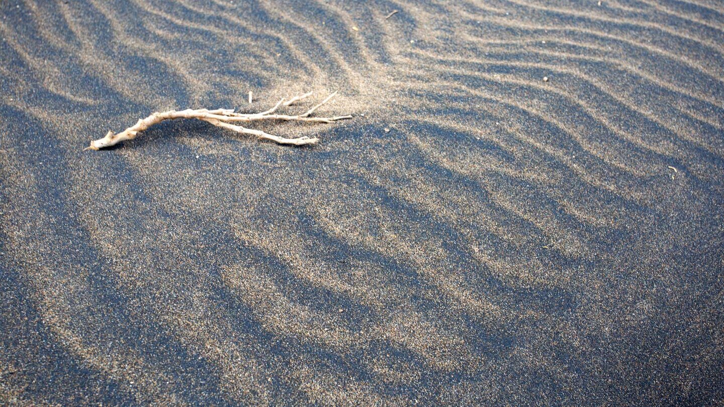 schwarz-braun gemaserter Sand am Strand