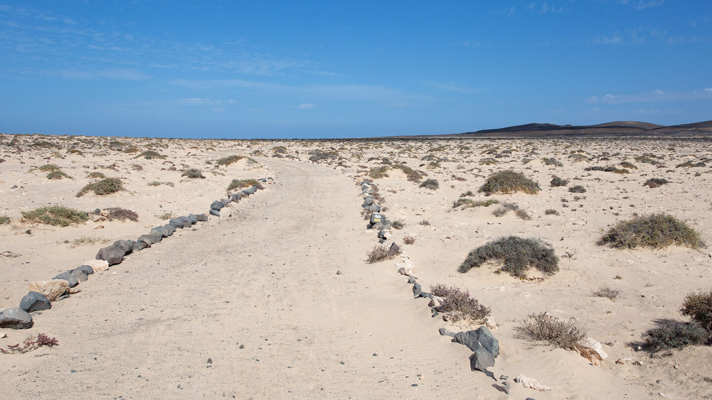 der mit Steinen begrenzte Wanderweg PR FV 56 durch eine karge Sandlandschaft der mit Steinen begrenzte Wanderweg PR FV 56 durch eine karge Sandlandschaft