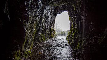 Wasser strömt im letzten Tunnel vor den Marcos Quellen aus dem Fels