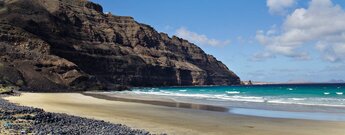 die Playa de Canteria bei Ebbe an den auslaufenden Klippen des Famara-Gebirges auf Lanzarote