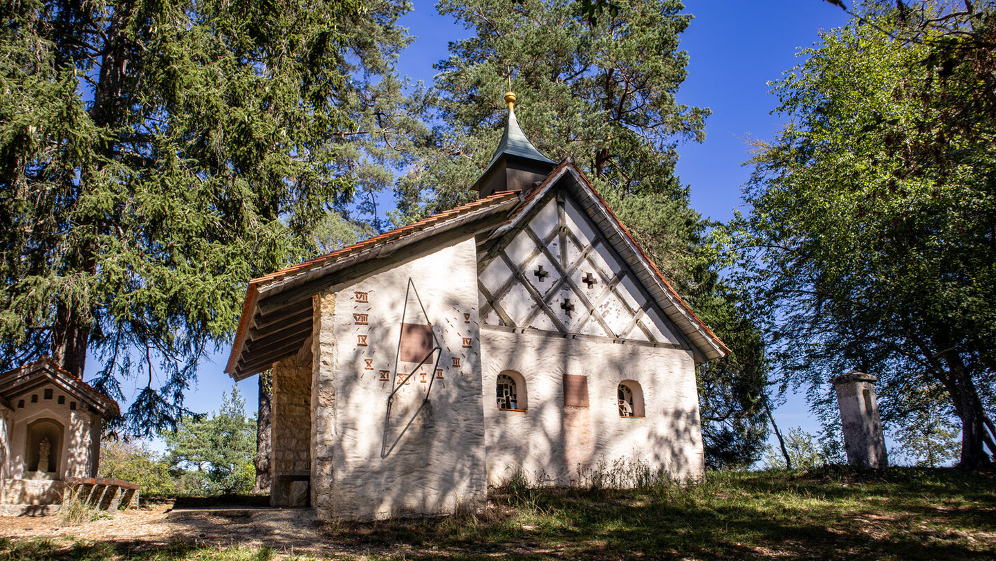 Fachwerk-Kapelle mit Sonnenuhr und Dachreiter im Wald des Donautals