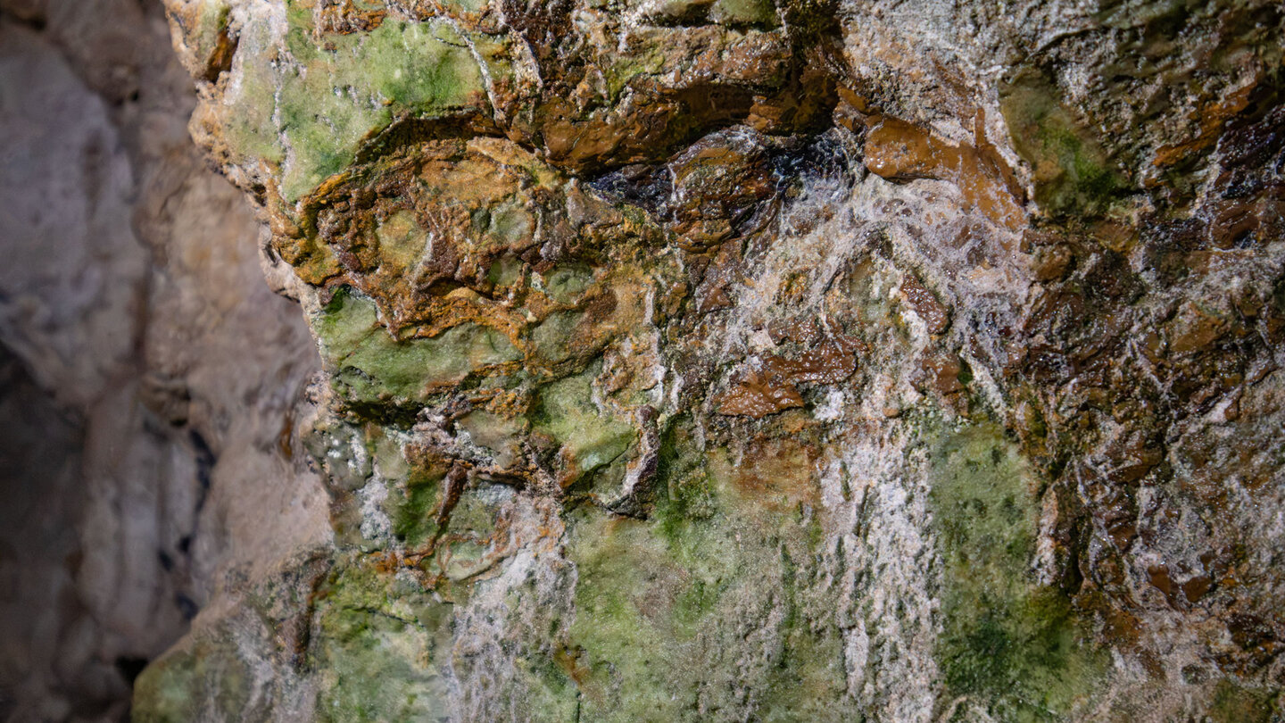Verwittertes Karstgestein mit grünen und ockerfarbenen Ablagerungen