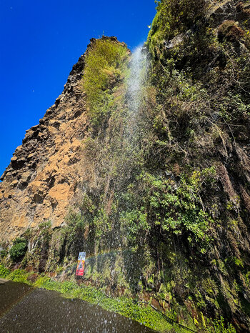 das Wasser des Cascata dos Anjos auf Madeira fällt auf die Straße und bildet Regenbögen