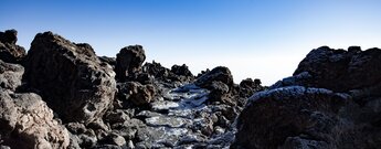 vereister Wanderweg über grobe Vulkansteine