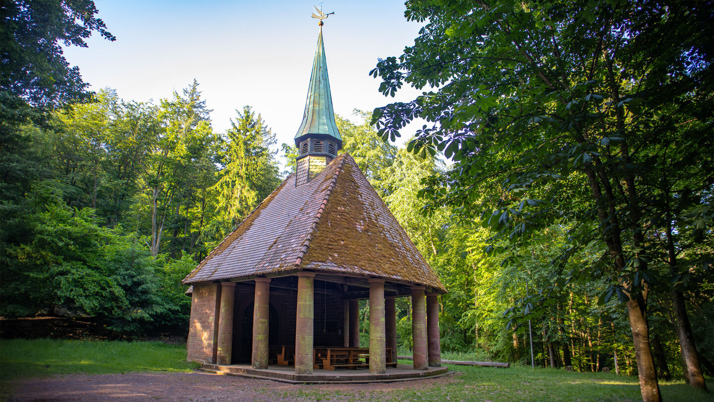 Das Winterkirchel – offene Waldkapelle mit Rundgang aus Sandsteinsäulen, Ziegeldach und kupfernem Turmhelm, umgeben von Laubbäumen
