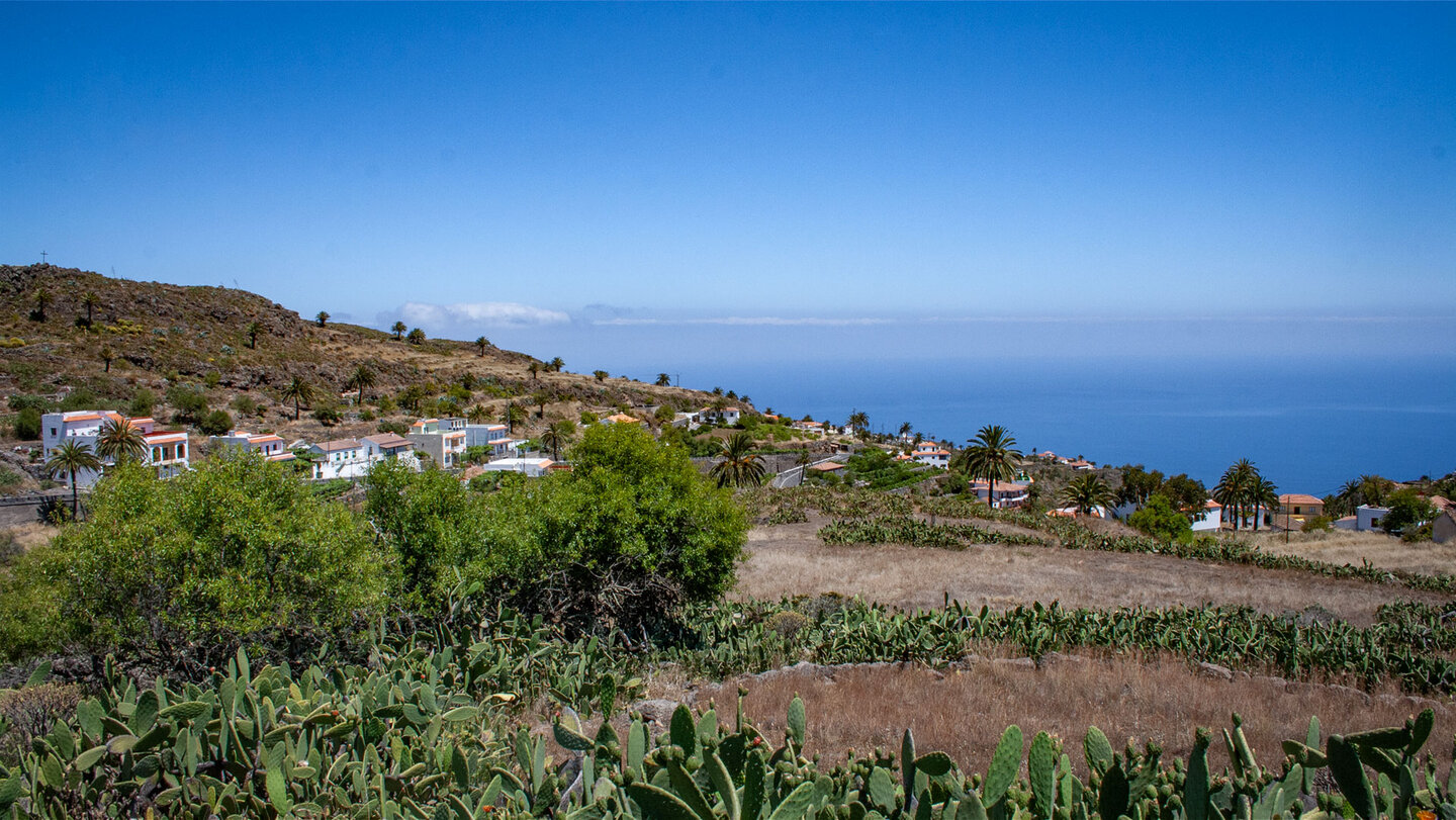 Blick über das Dorf Alajeró mit Feigenkakteen und Palmen zum Atlantik, La Gomera.