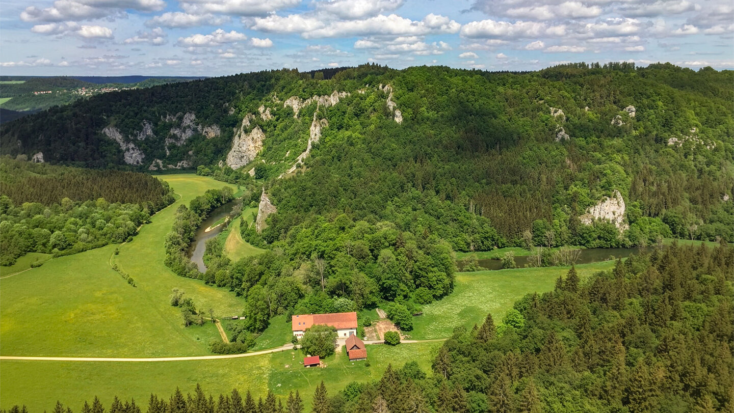 Bauernhof mit rotem Dach zwischen Wiesen und Donauschleife