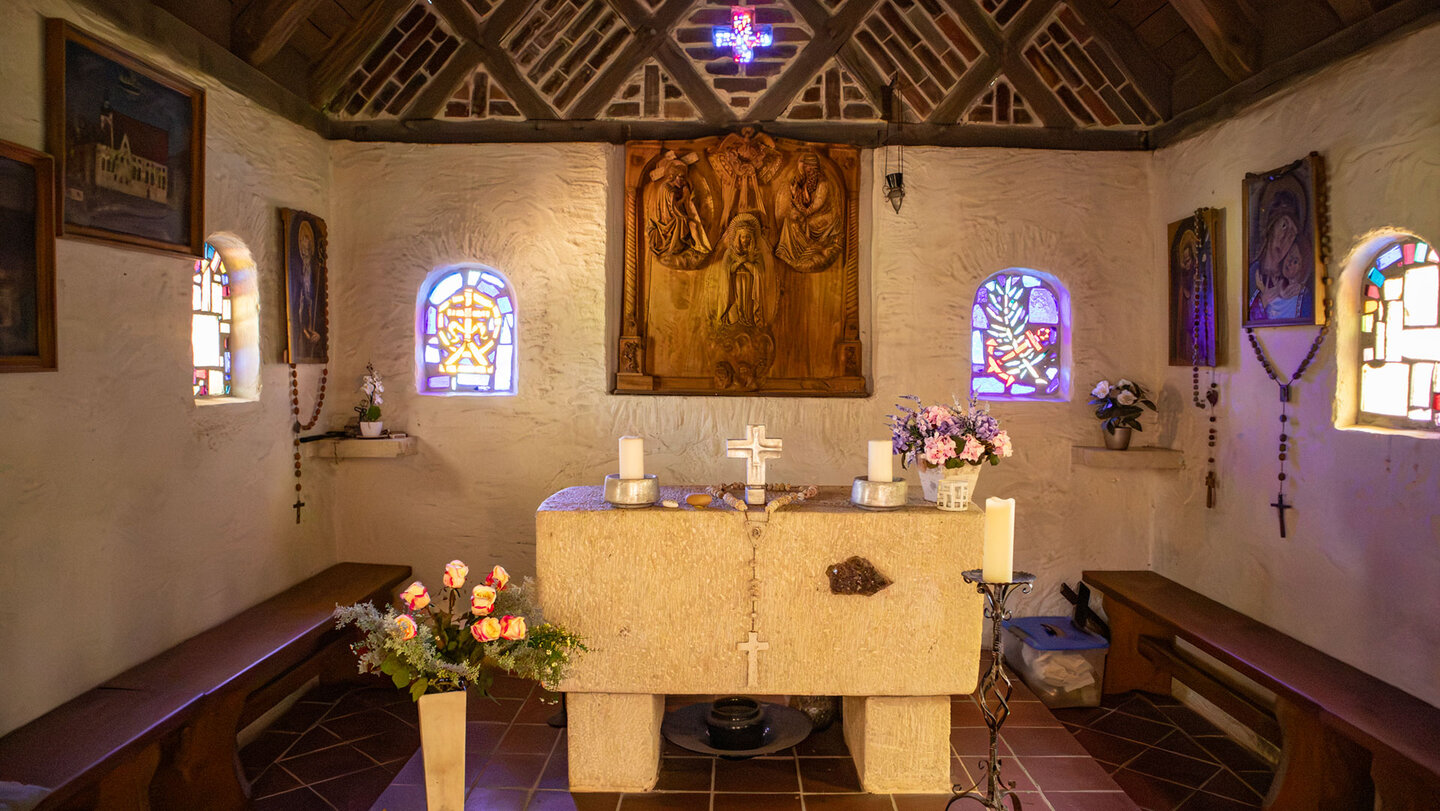Altarraum einer kleinen Einsiedlerkapelle im Donautal mit religiösen Bildern an den Wänden.