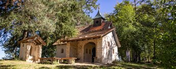 Kleine verputzte Kapelle mit Glockenturm und Kreuz im Wald des Donautals.