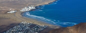 Bucht von Famara mit Feriensiedlung und dem Fischerdorf Caleta de Famara weiter hinten