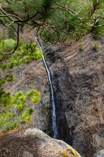 schmaler Wasserfall vor einer steilen Felswand