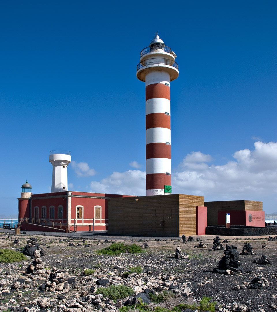 das rote Hauptgebäude mit den drei Türmen des Faro de el Tostón auf Fuerteventura