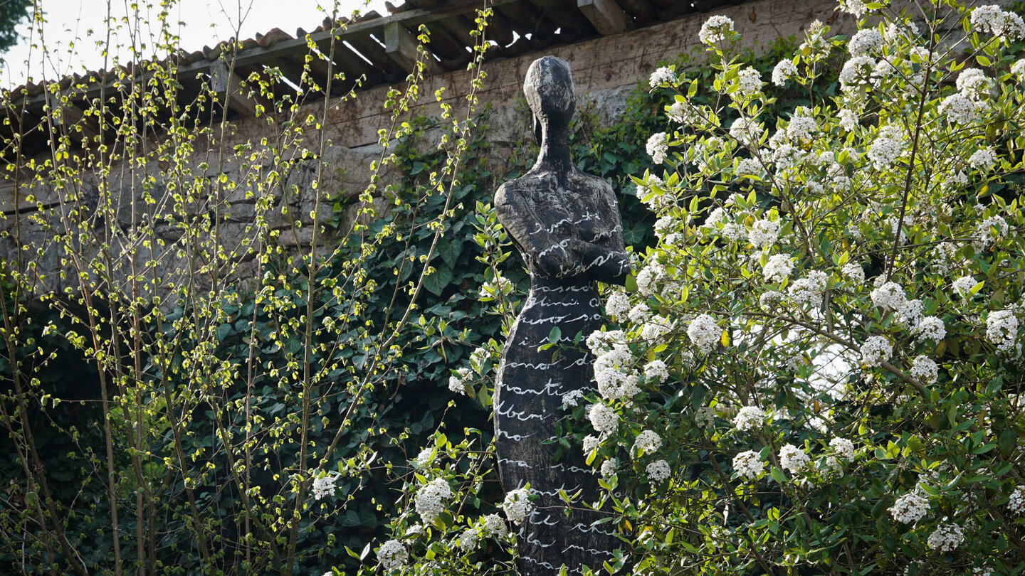 hinter Blüten versteckte Skulptur