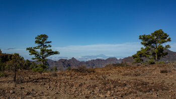 Blick über einen steilen Berggrat zur Nachbarinsel Teneriffa mit dem Teide