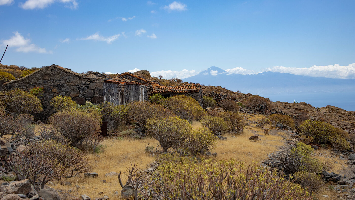 Panorama mit Ruinenhäusern und aufgegebenen Terrassen mit der Silhouette des Teide