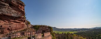 Die Burgruine Drachenfels thront auf ihrem Felssporn über der offenen Kulturlandschaft bei Busenberg.