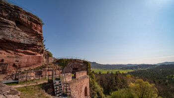 Die Burgruine Drachenfels thront auf ihrem Felssporn über der offenen Kulturlandschaft bei Busenberg.