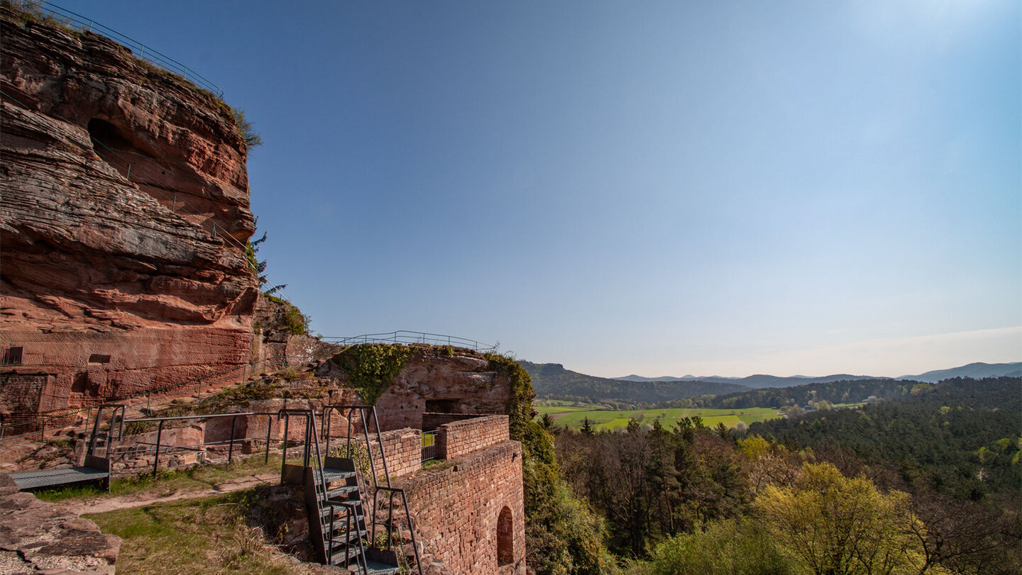 Die Burgruine Drachenfels thront auf ihrem Felssporn über der offenen Kulturlandschaft bei Busenberg.