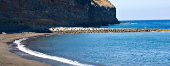 der saubere Strand der Playa de La Cueva auf La Gomera ist durch eine Hafenmole geschützt