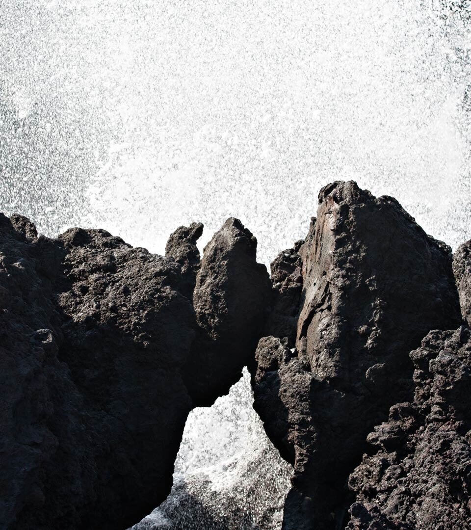 ein gischtumtostes Felstor im Basaltgestein an der Küste bei Tinajo