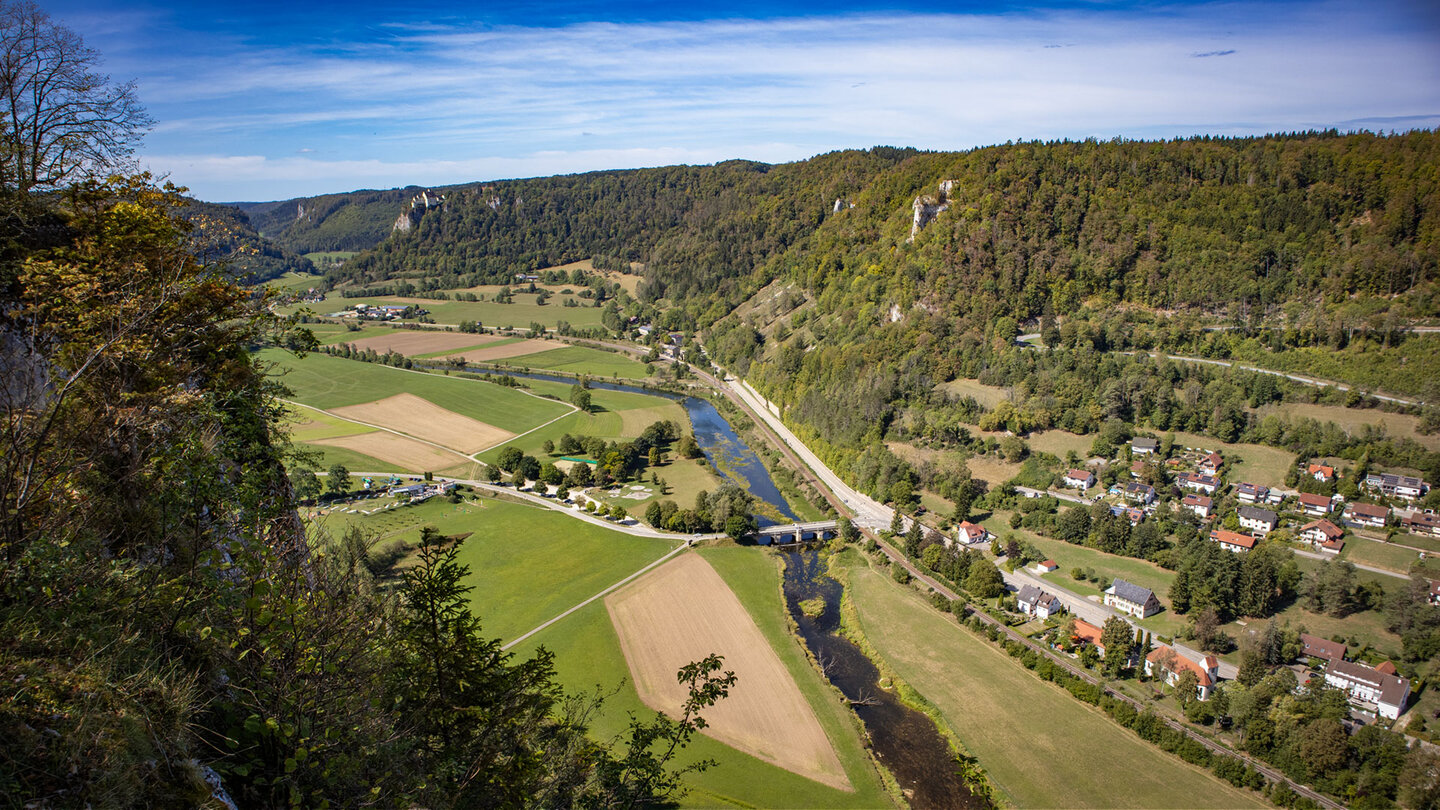 Weites Donautal mit Fluss, Dorf und Felsformationen, im Hintergrund Schloss Werenwag.