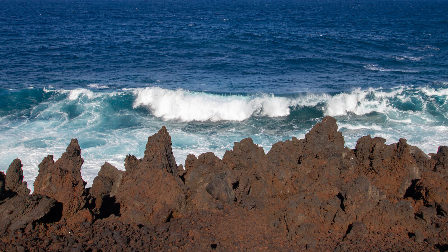 rötlich-braun gefärbte Lavaspitzen vor dem tiefblauen Atlantik