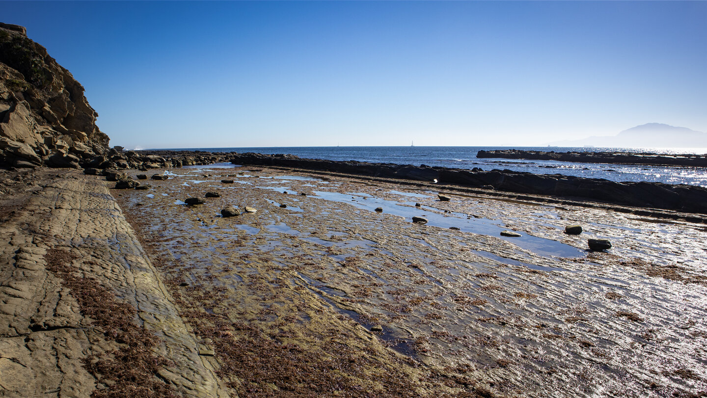 Bei Ebbe sind die Klippen und die Schichtungen der Felsen des Flysch del Estrecho zu sehen