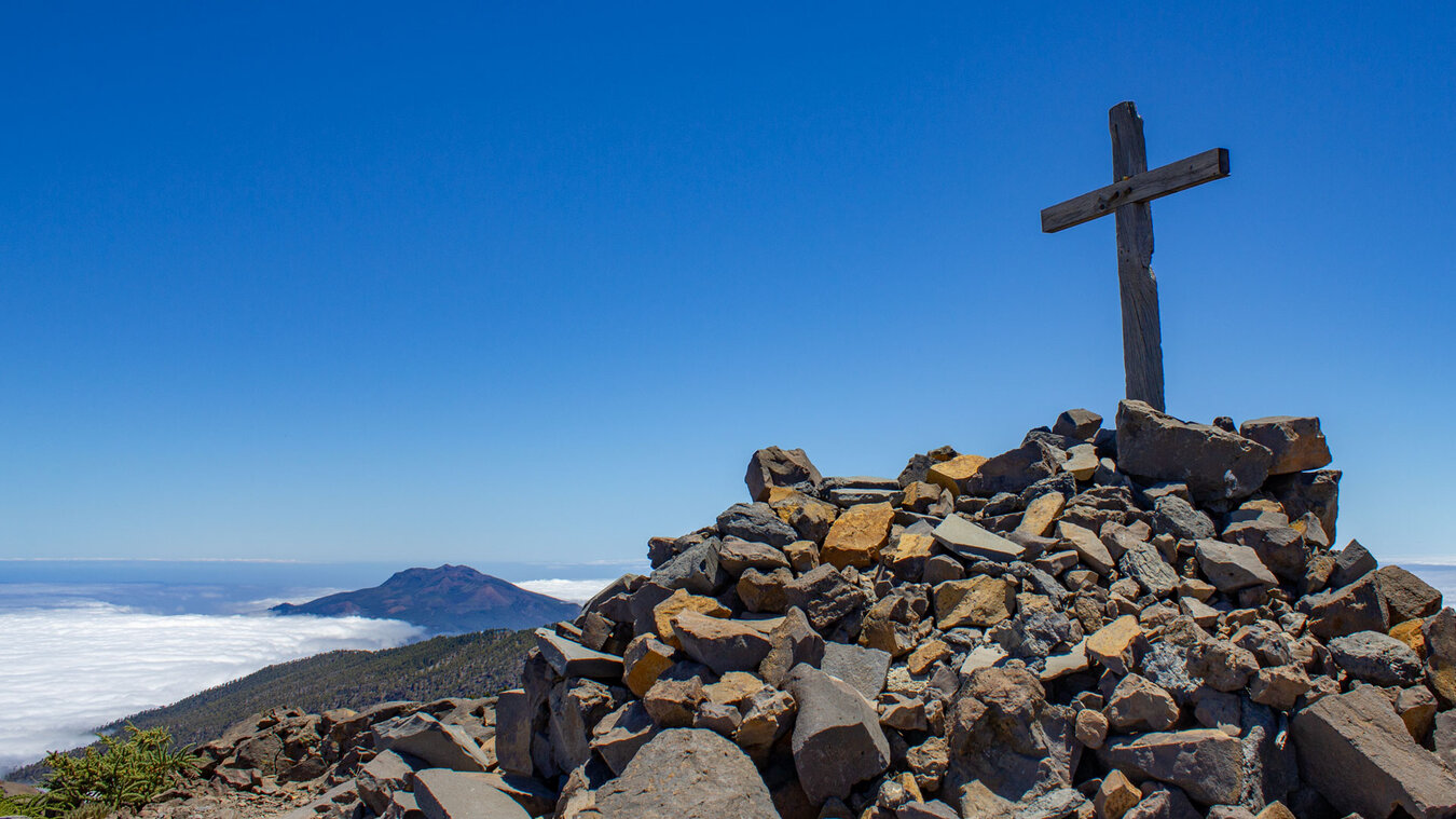 das Gipfelkreuz am Pico de las Nieves mit den Vulkanen der Cumbre Vieja  | © SUNHIKES